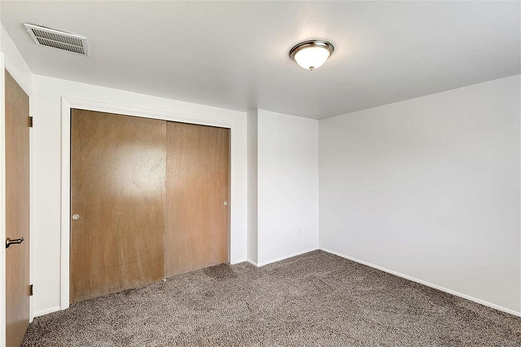A room with a carpeted floor and a wooden door.