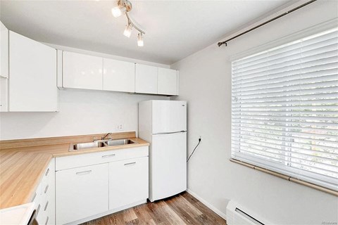 A white kitchen with a wooden counter top and white cabinets.