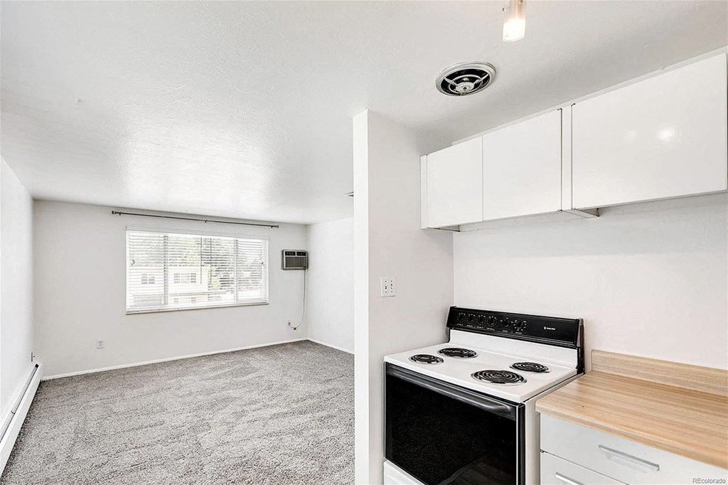 A kitchen with a stove top oven and a window with blinds.