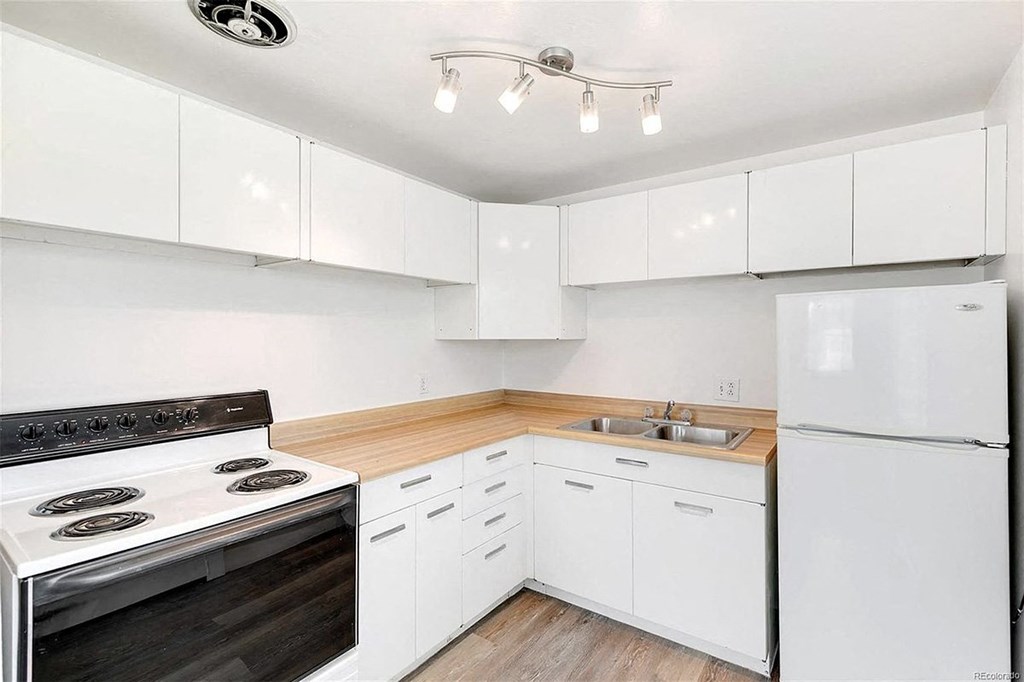 A white kitchen with a black stove top oven.