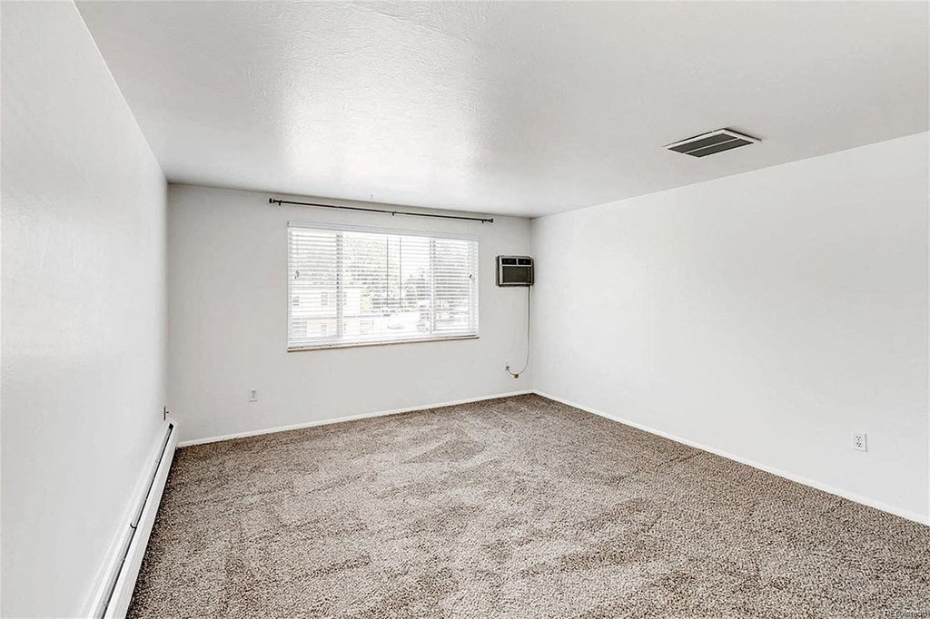A room with a window and carpeted floor.