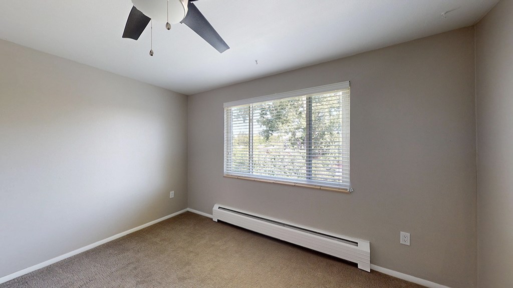 A room with a ceiling fan and a window with blinds.
