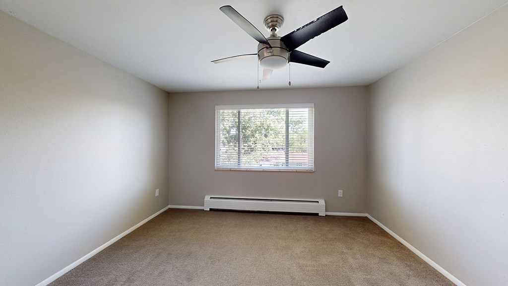 A room with a ceiling fan and a window with blinds.