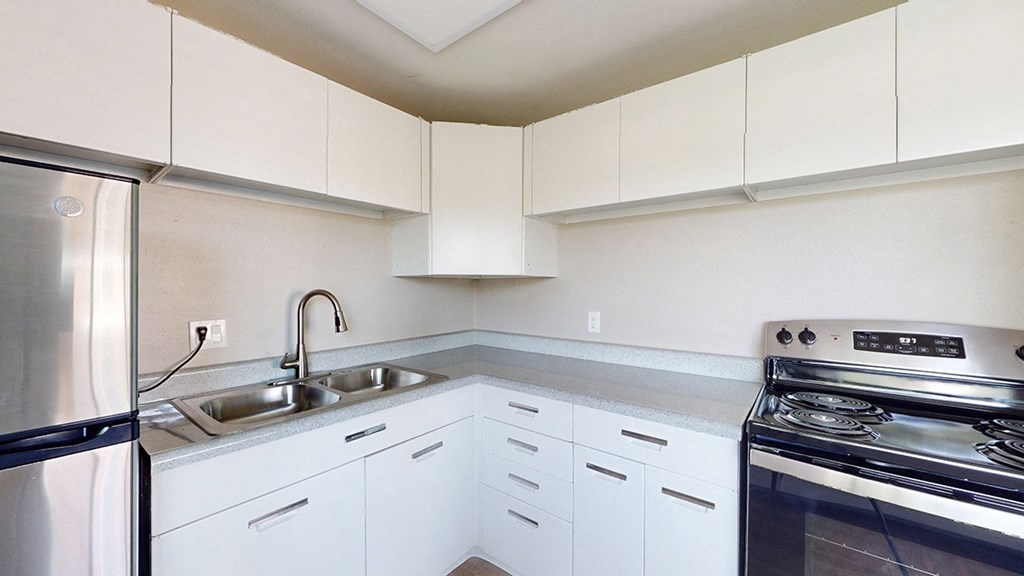 A kitchen with white cabinets and a stainless steel refrigerator.