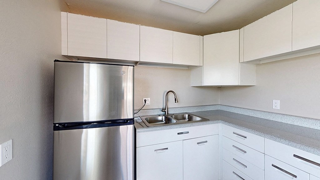 A kitchen with a stainless steel refrigerator and white cabinets.
