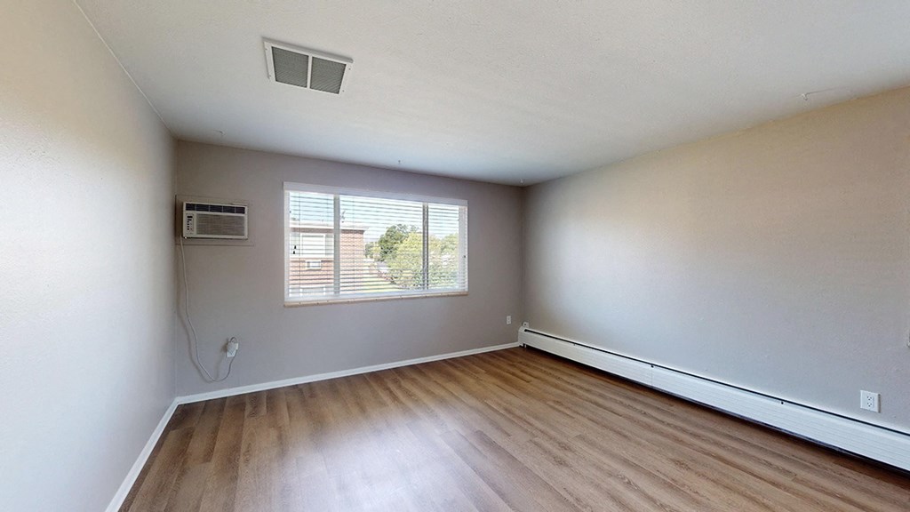A room with wooden flooring and a window with blinds.