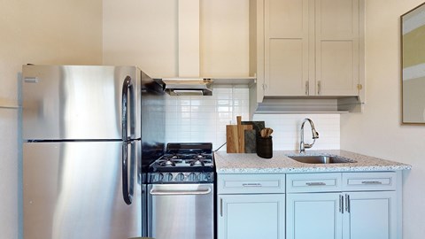 A kitchen with a stainless steel refrigerator and a stove top oven.