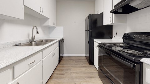 A modern kitchen with white cabinets and black appliances.