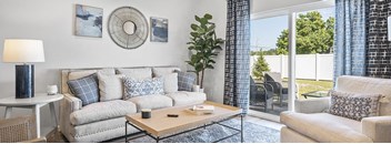 A living room with a sofa, a coffee table, a side table, and a potted plant.