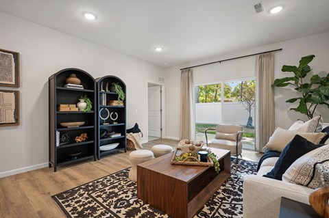 A living room with a wooden coffee table and a large window with curtains.