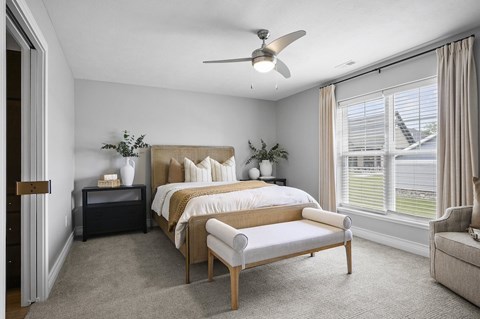 A bedroom with a large bed and a window with blinds.