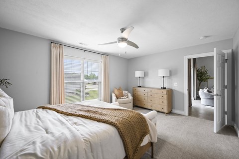 A bedroom with a large bed and a ceiling fan.