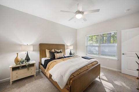 A bedroom with a bed, nightstand, and window.