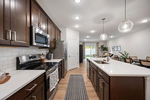 A modern kitchen with dark brown cabinets and white countertops.