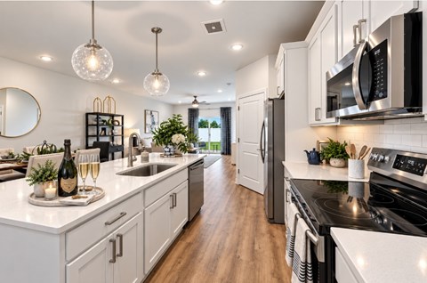 A modern kitchen with white cabinets and a black stove top.