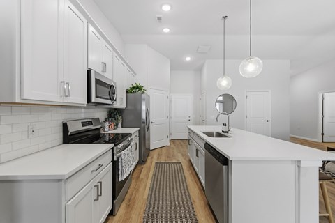 A modern kitchen with white cabinets and stainless steel appliances.