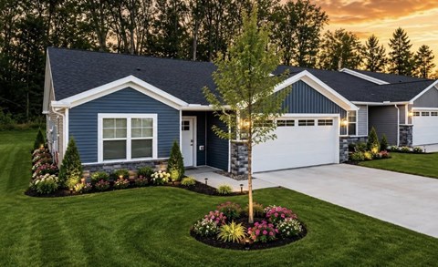 A blue house with a white garage door and a tree in the front yard.