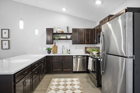 A modern kitchen with a stainless steel refrigerator and dark wood cabinets.