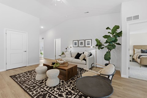 A living room with a white couch, a coffee table, and a plant.