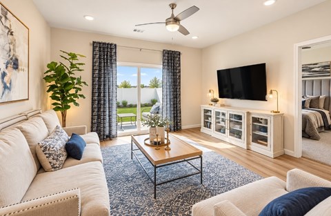 A living room with a white couch, a coffee table, and a flat screen TV mounted on the wall.