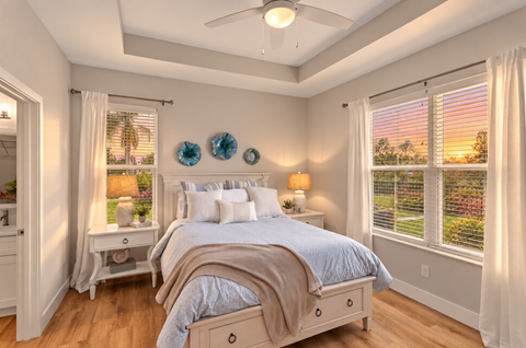A bedroom with a bed, nightstand, and window with blinds.