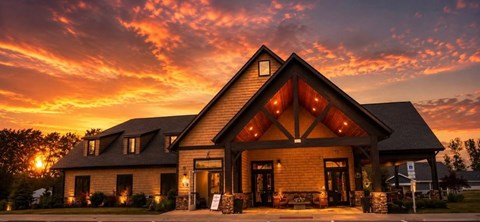 A house with a triangular roof and a stone facade is illuminated by the setting sun.