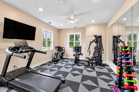 A spacious home gym with a treadmill, exercise bike, and a variety of weights.