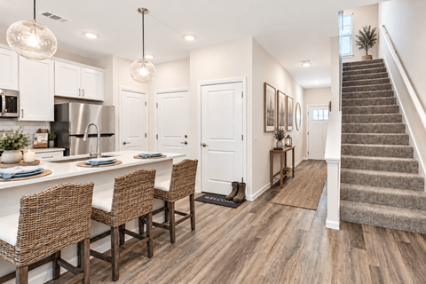 A kitchen with white cabinets and a dining table with chairs.
