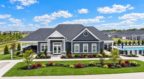 A house with a grey roof and white trim is surrounded by a well-manicured lawn and a variety of plants.