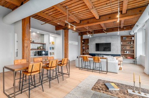 A modern living room with a wooden ceiling and a long table with chairs.
