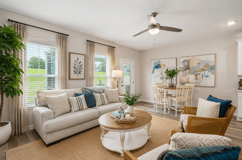 A living room with a white couch, a coffee table, and a ceiling fan.