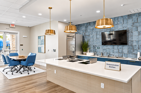 A demonstration kitchen with a blue chair set and a white counter.