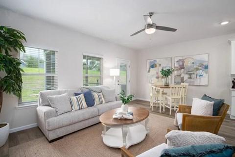 A living room with a couch, chairs, and a ceiling fan.