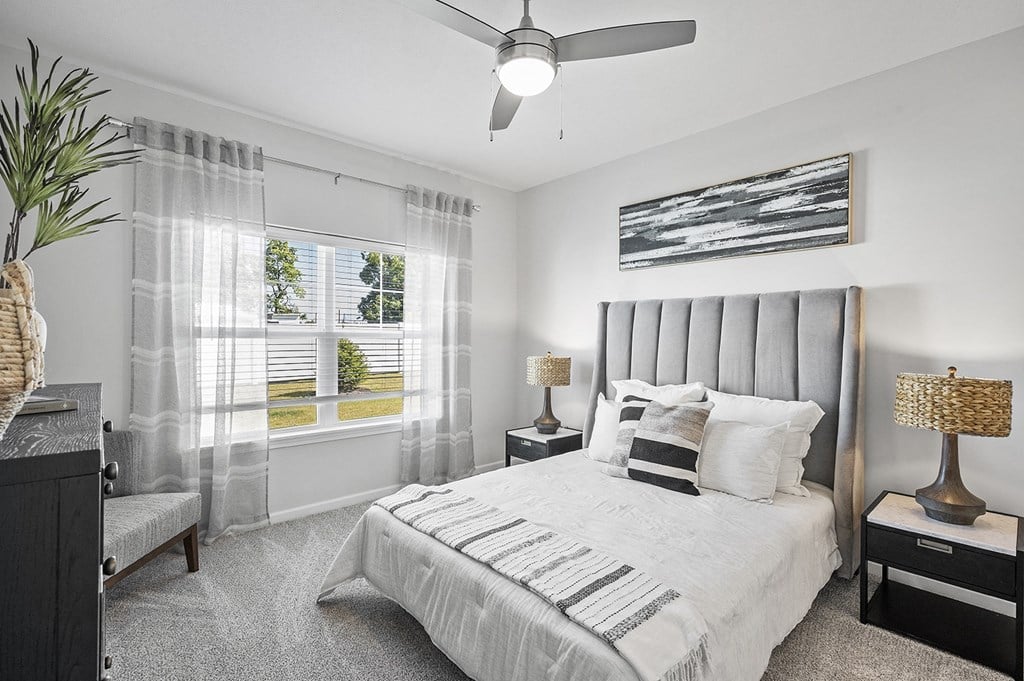 A bedroom with a large bed and a ceiling fan.