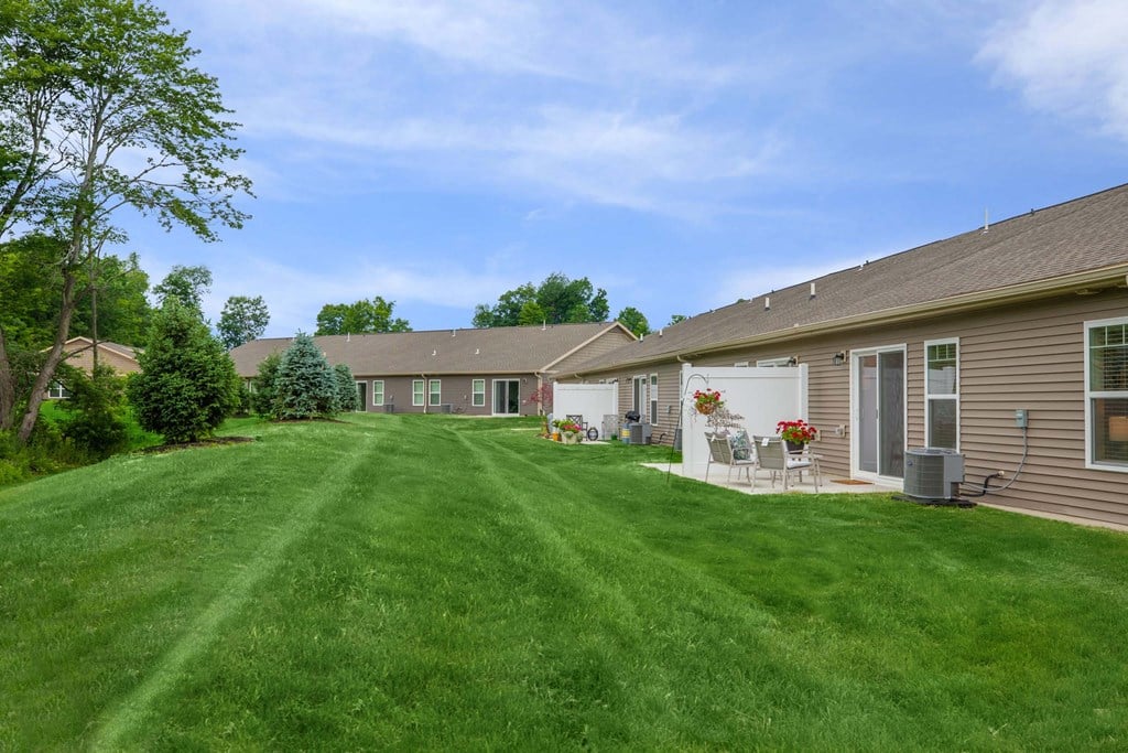 A grassy yard in front of a house with a lawn chair and table set up.