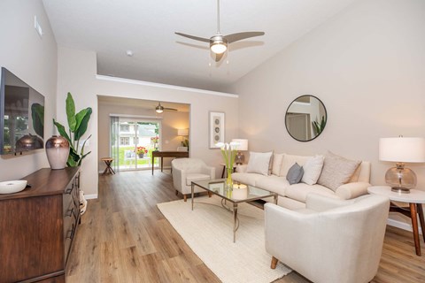 A modern living room with a white sofa and a wooden floor.
