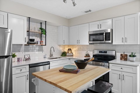 A kitchen with a wooden table and white cabinets.