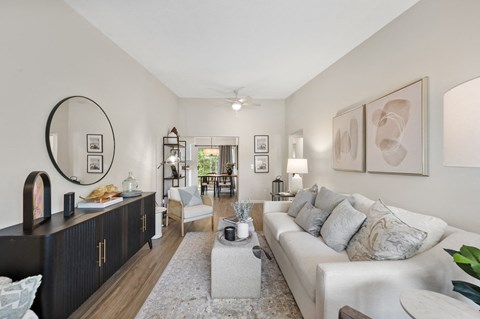 A living room with a white couch and a large mirror on the wall.