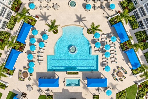 A large swimming pool surrounded by blue loungers and umbrellas.