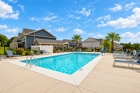 A swimming pool surrounded by lounge chairs and palm trees.