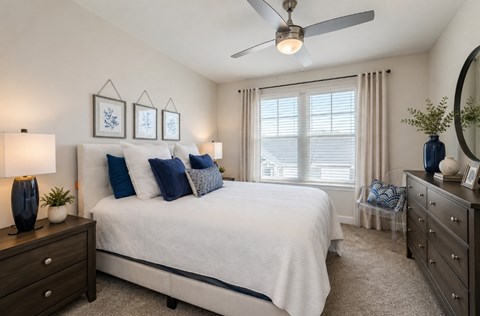 A bedroom with a bed, dresser, and ceiling fan.