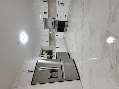 A kitchen with a marble wall and stainless steel appliances.