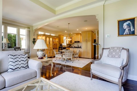 A living room with a white sofa, a glass coffee table, and a painting on the wall.