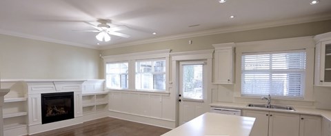 A large, empty room with a fireplace and a kitchen area.