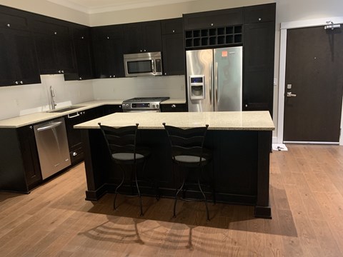 A kitchen with black cabinets and a white island.