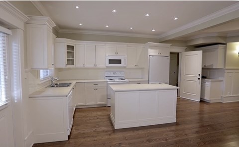 A kitchen with white cabinets and appliances.