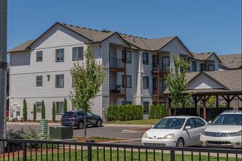 A row of townhouses with cars parked in front.