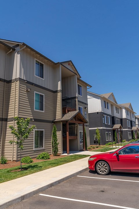 A red car is parked in a parking lot in front of a building at Northplace Apartment Homes, Salem