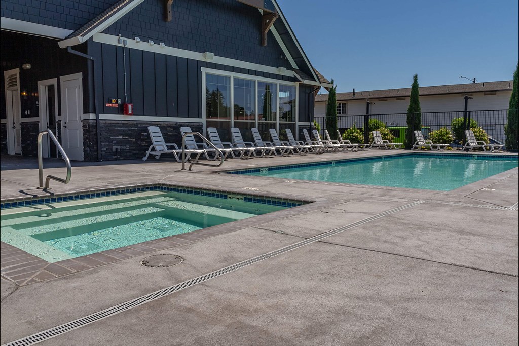 A pool with a slide and lounge chairs outside a house. A pool with a slide and lounge chairs outside a house at St Helens Place Apartment Homes, St Helens, 97051