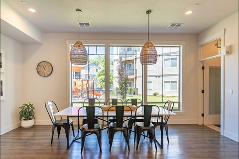 A dining room with a table and chairs and a clock on the wall.